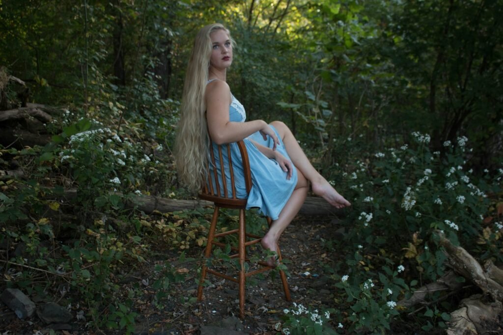 a woman sitting on a chair in the woods